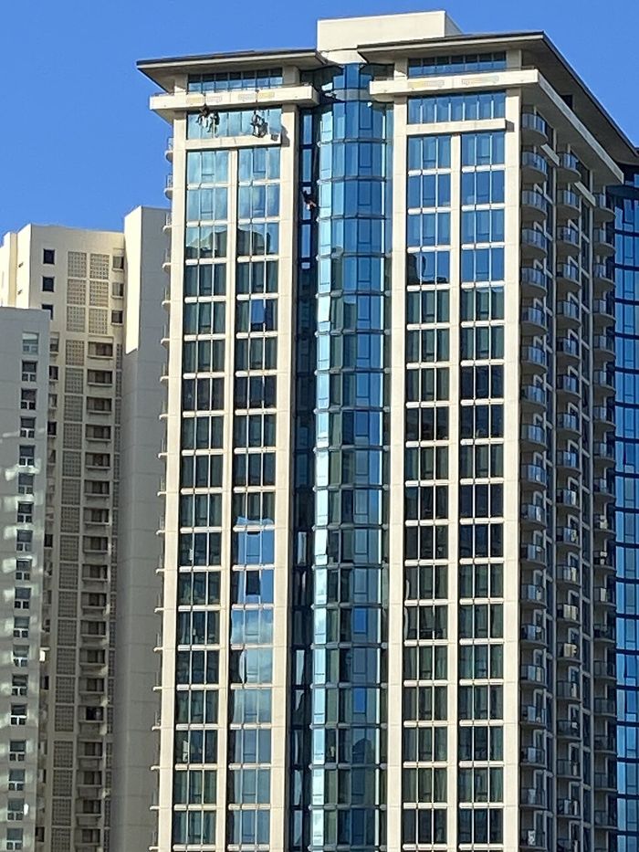 Technicians cleaning windows on a high-rise tower